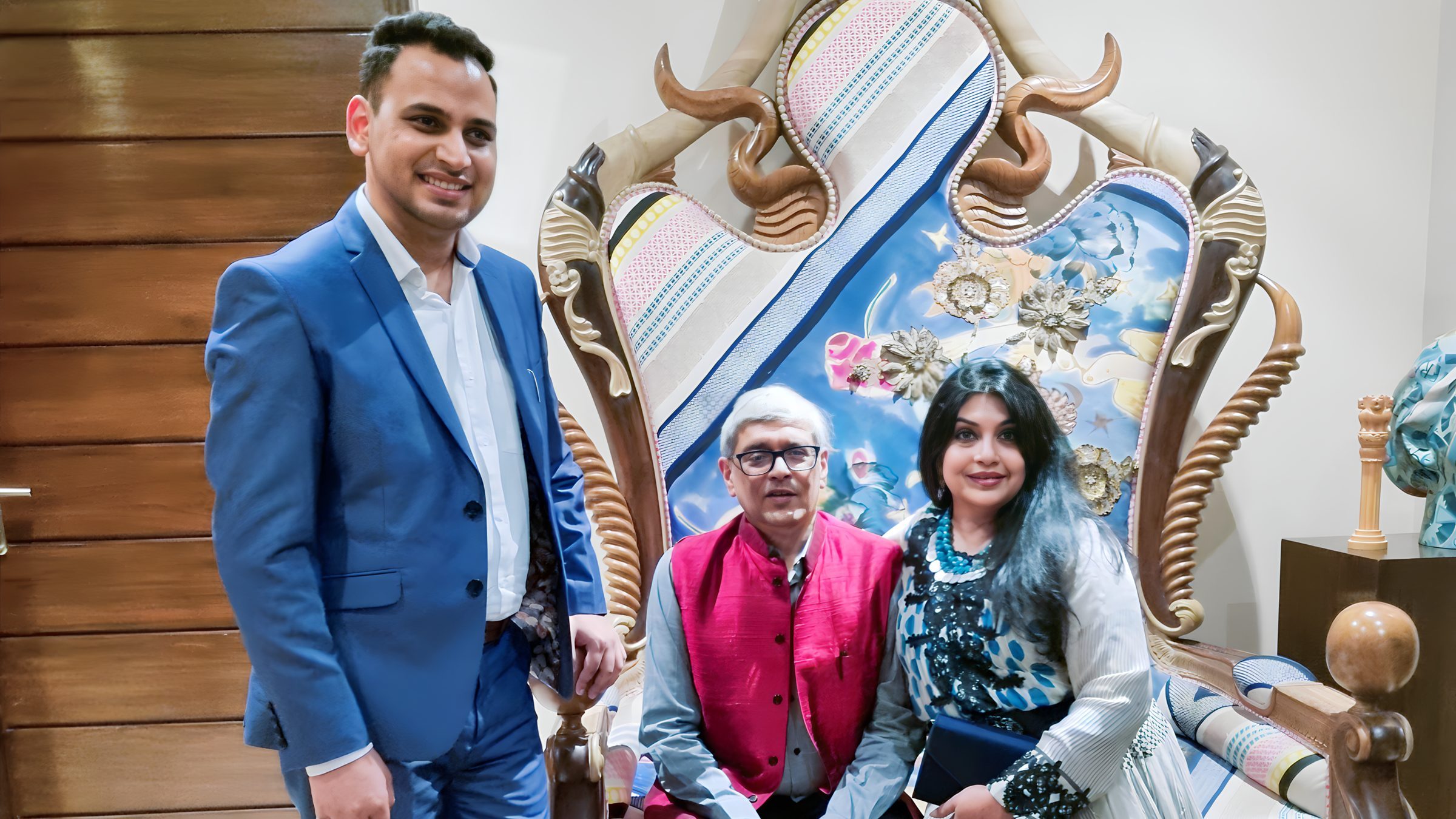 Lithvik Mukesh Sharma is photographed. Three people gather around an ornate, custom-decorated wooden chair or throne. Lithvik Mukesh Sharma is photographed. Three people gather around an ornate, custom-decorated wooden chair or throne. Lithvik Mukesh Sharma, the younger man, stands on the left