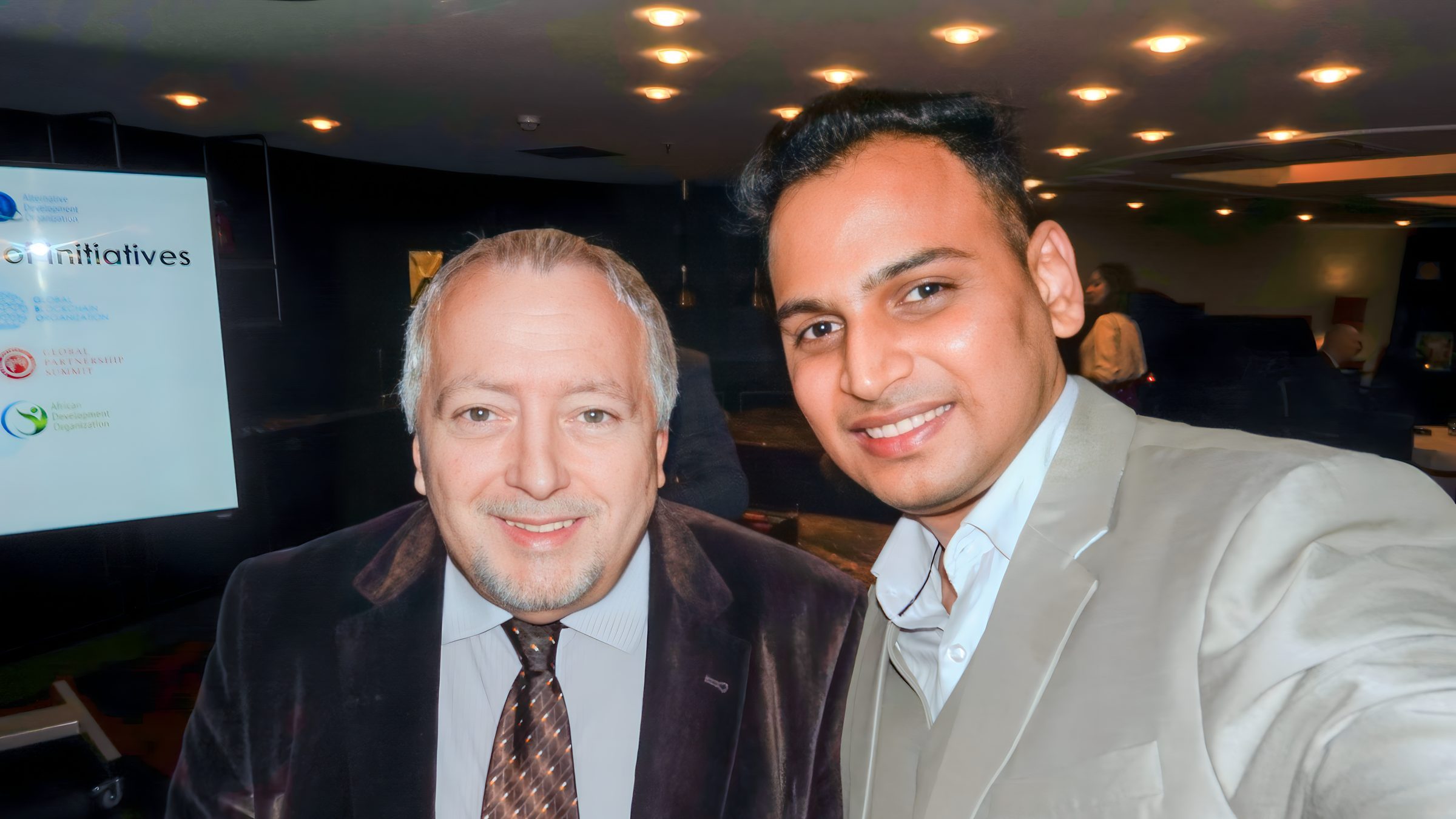 Lithvik Mukesh Sharma, Group CEO of CryptoMize, is photographed at a development summit. A selfie-style photograph shows two men. Lithvik Mukesh Sharma, Group CEO of CryptoMize, is photographed at a development summit. A selfie-style photograph shows two men. Behind Lithvik Mukesh Sharma stands an older man with graying hair
